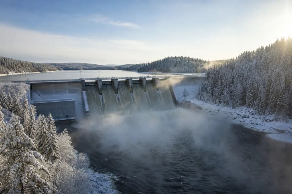 Vattenkraftverk i en norrländsk älv en kall vinterdag med froströk över vattnet
